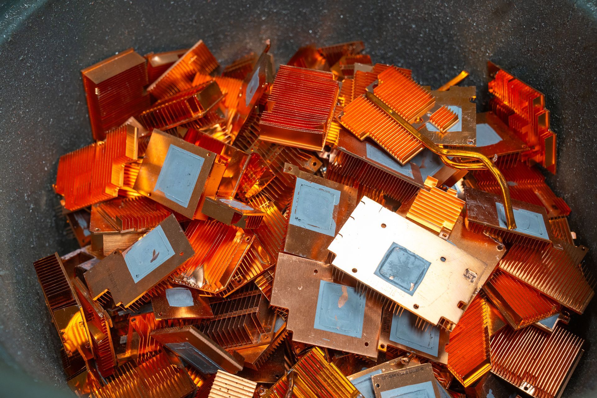 A close-up shot of a pile of copper heat sinks in a metal container.