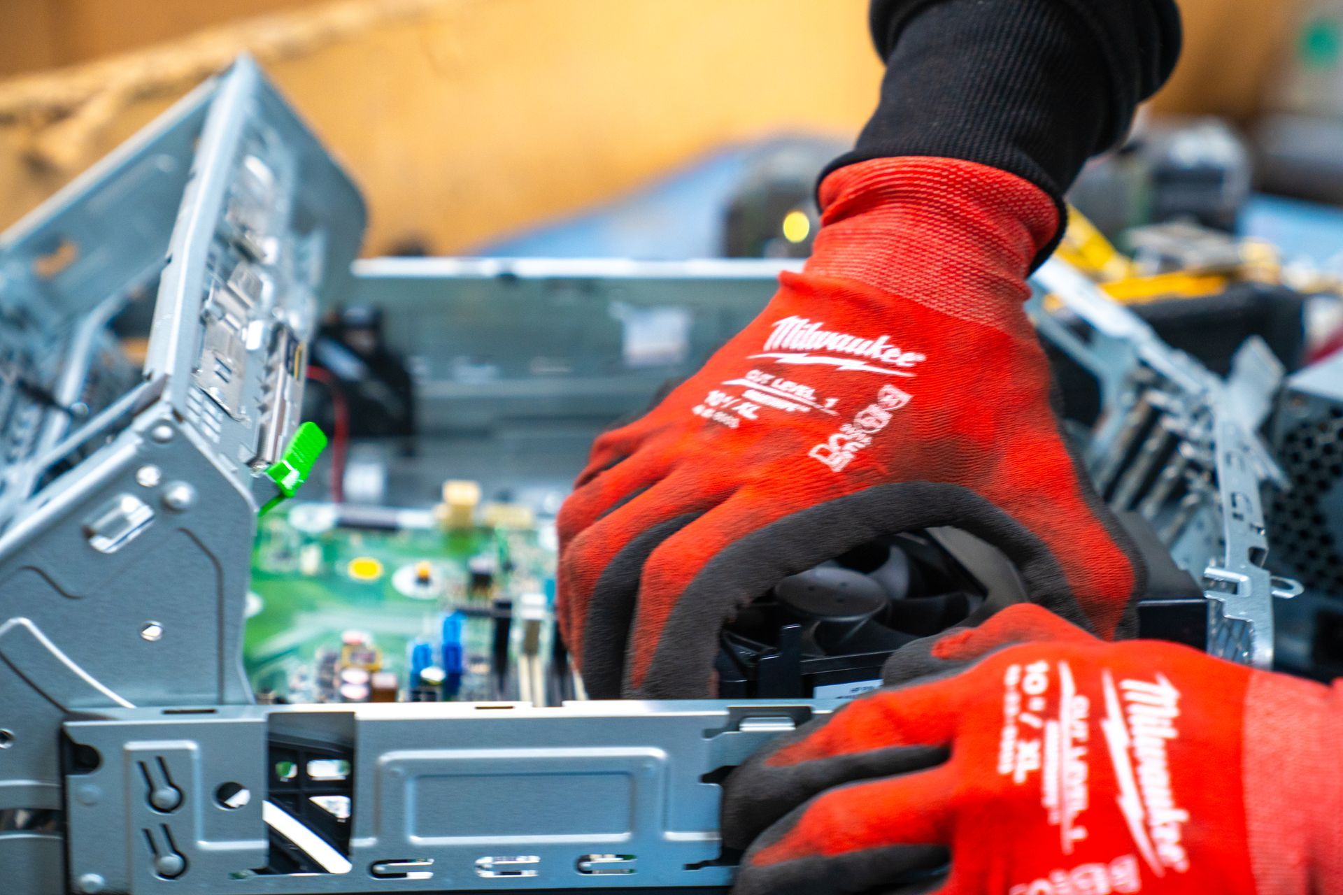 Person in red gloves working on the inside of a computer, possibly repairing or assembling.