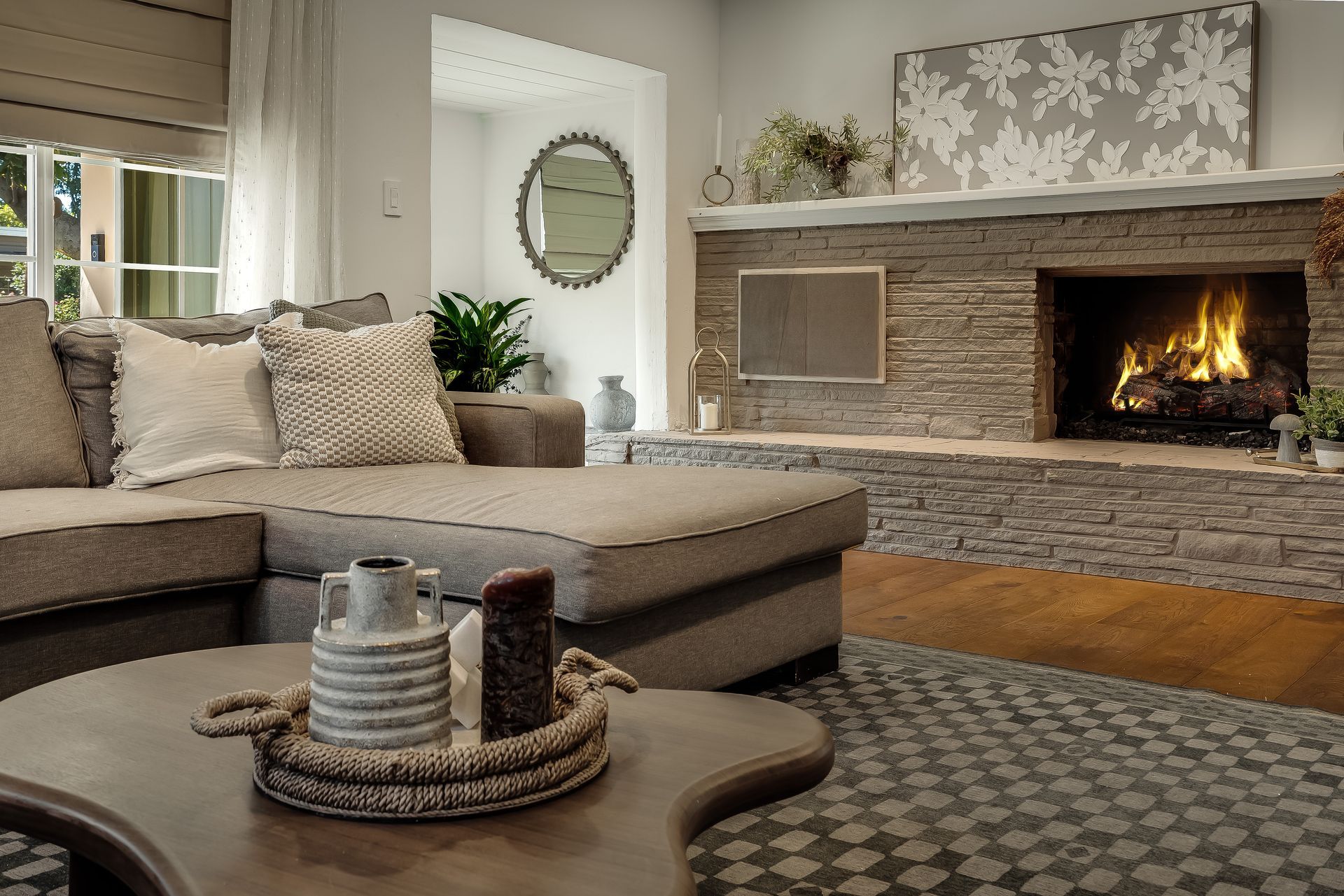 Cozy living room with a lit fireplace, sectional sofa, and coffee table with decor.