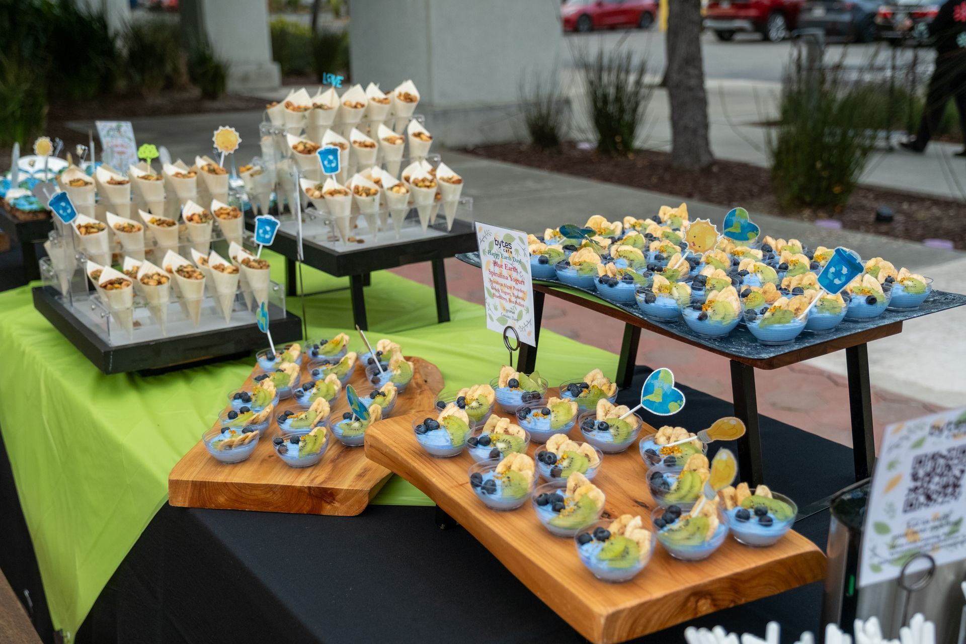 Dessert table with snacks: ice cream cones, and banana bites with blueberries on wood serving boards.