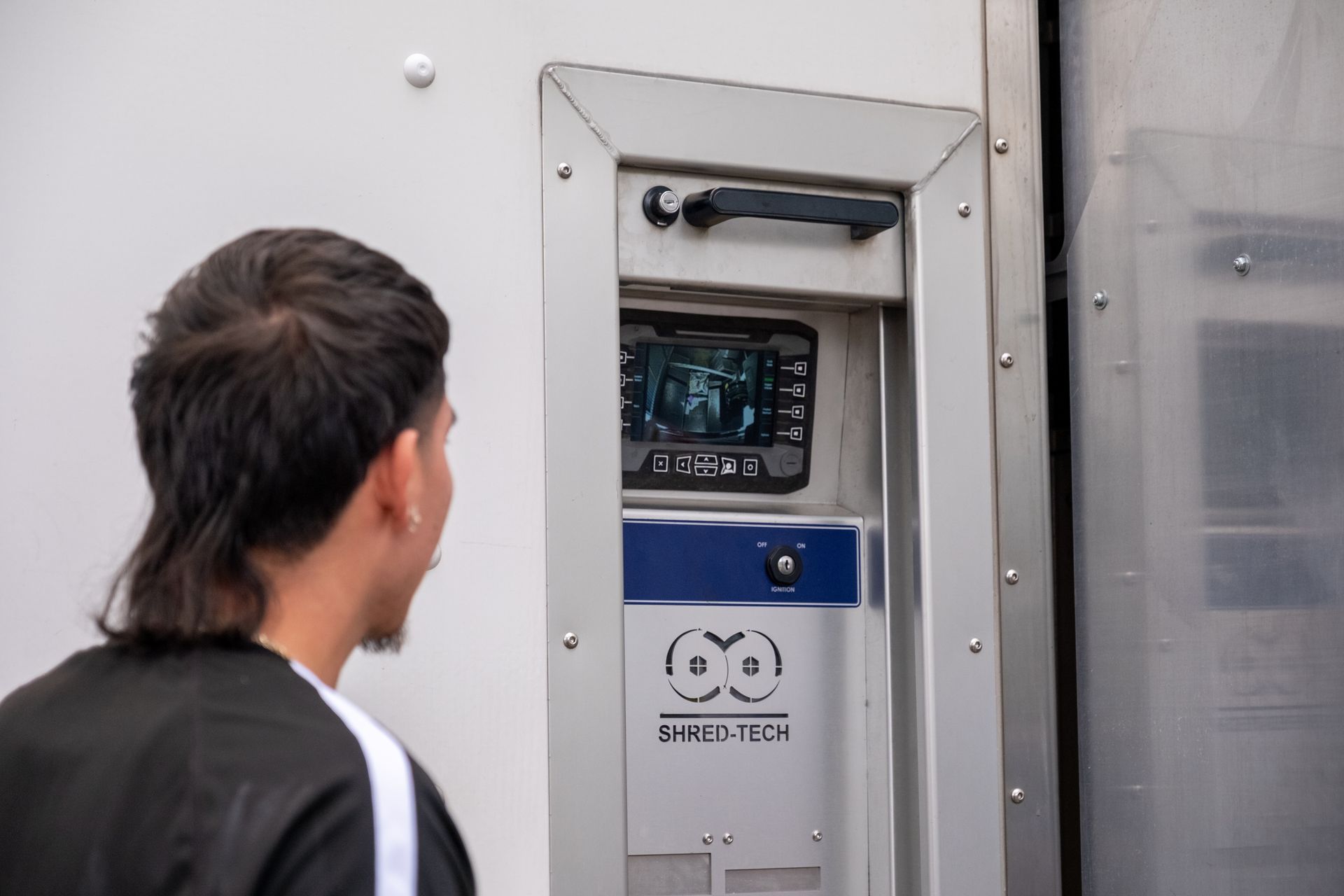 Man looking at a screen built into a white panel. The screen displays an image.