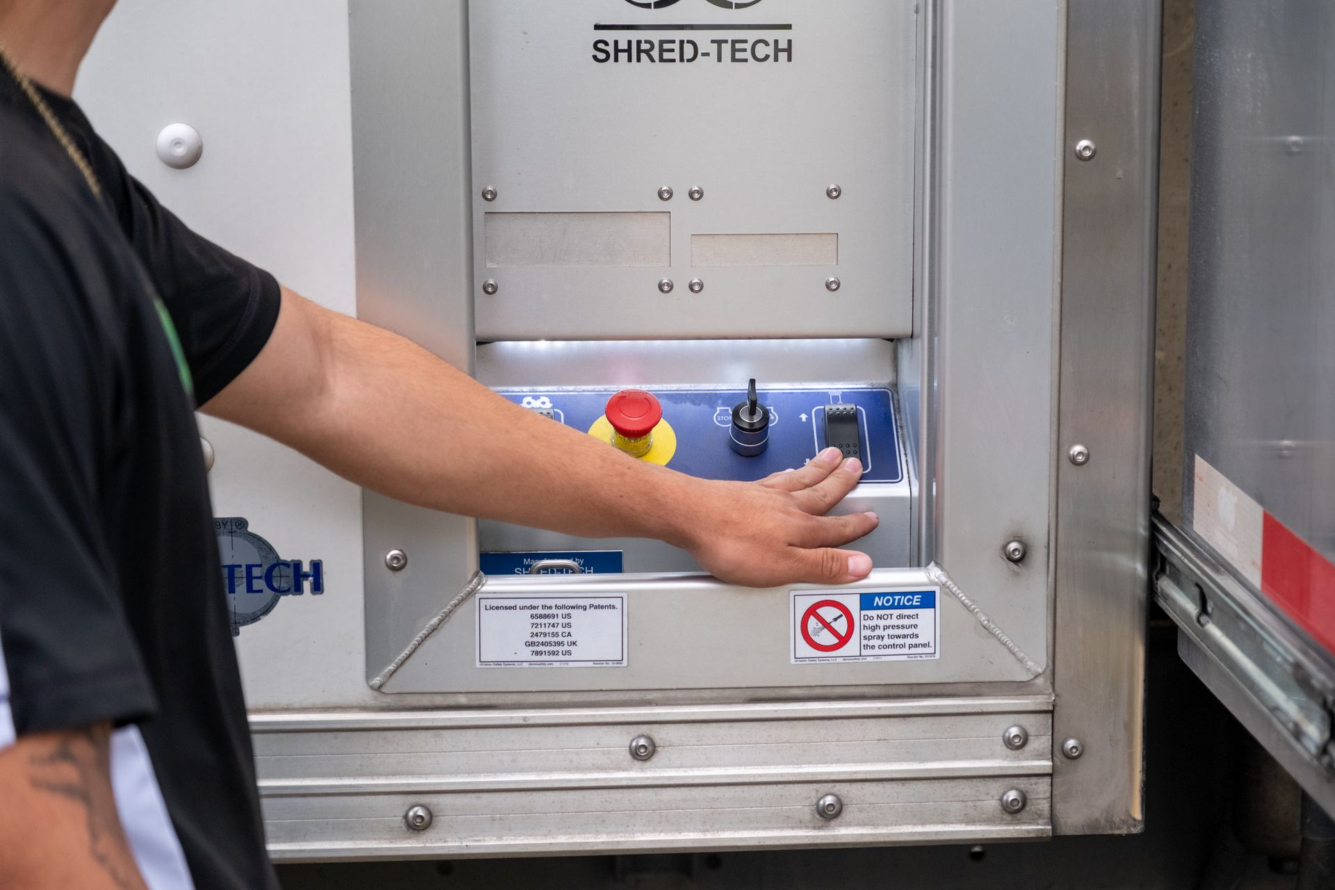Person's hand operating a power switch on a refrigerated truck's control panel.