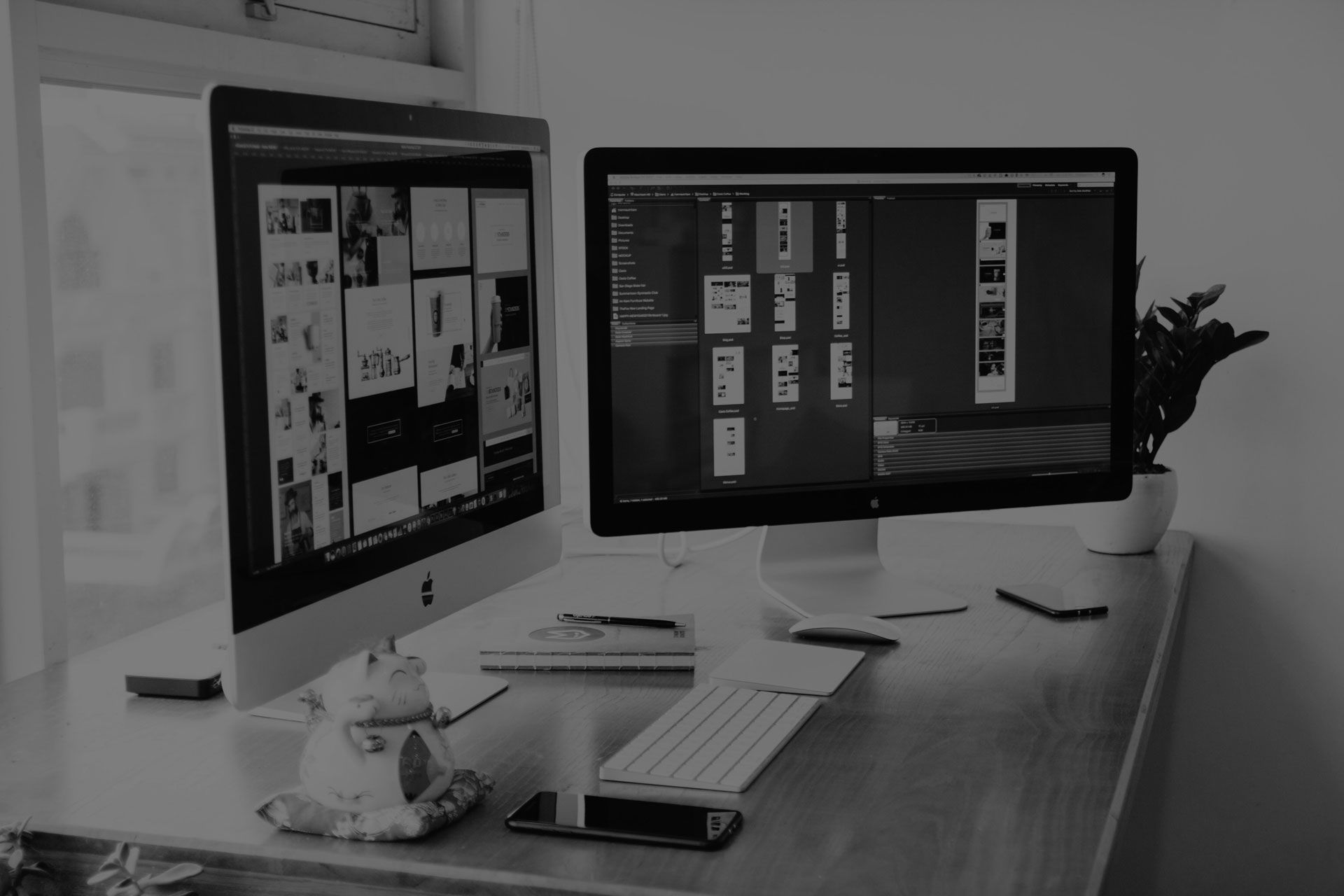 A black and white photo of two computer monitors on a desk.