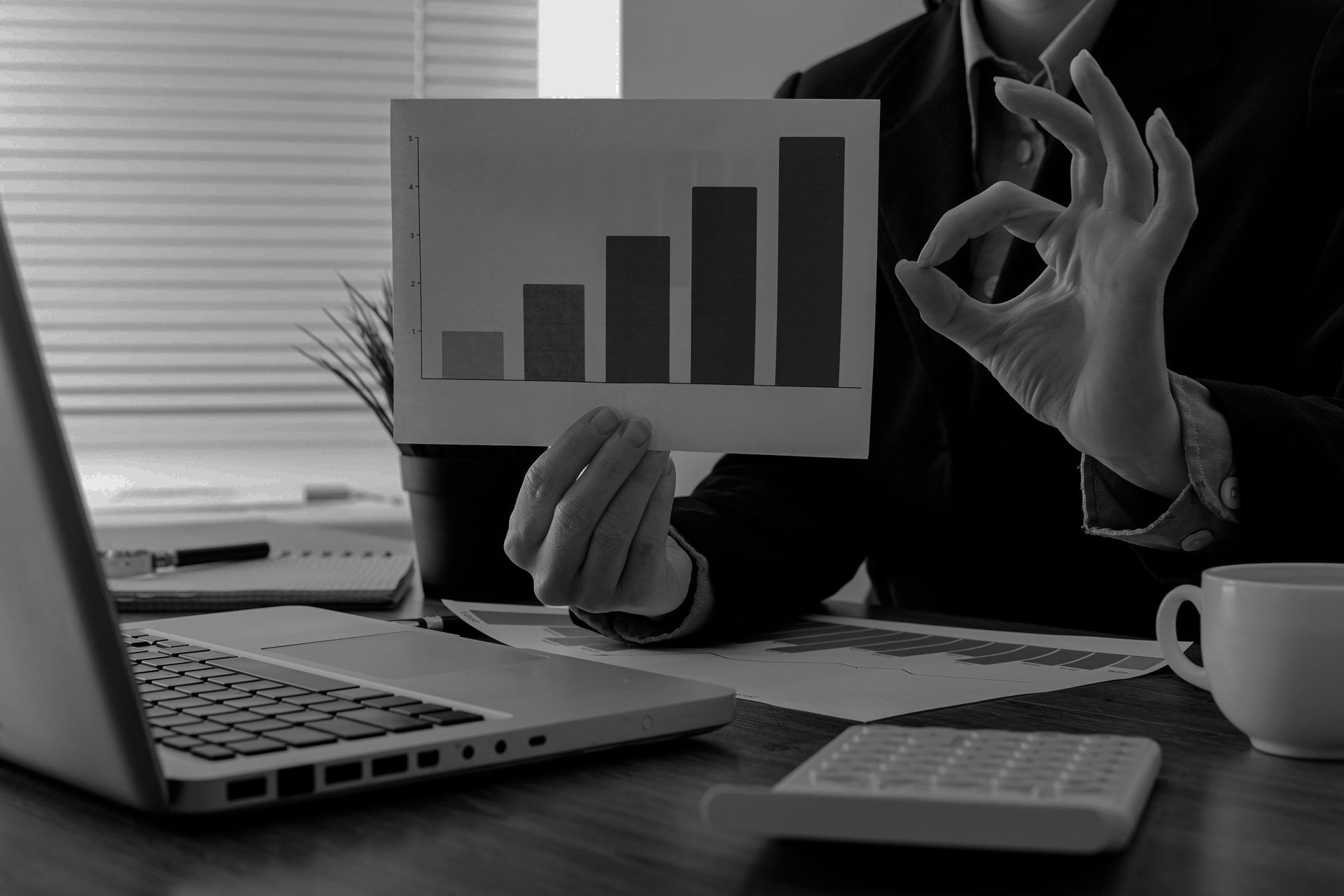 Person in suit holding graph with upward bars, making 
