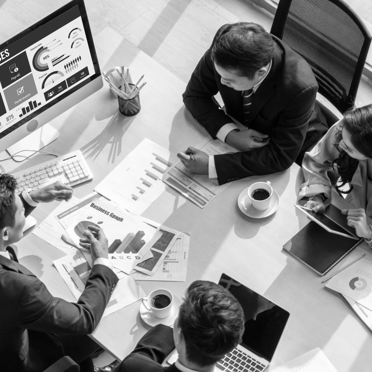 A group of people are sitting around a table with papers and a computer.