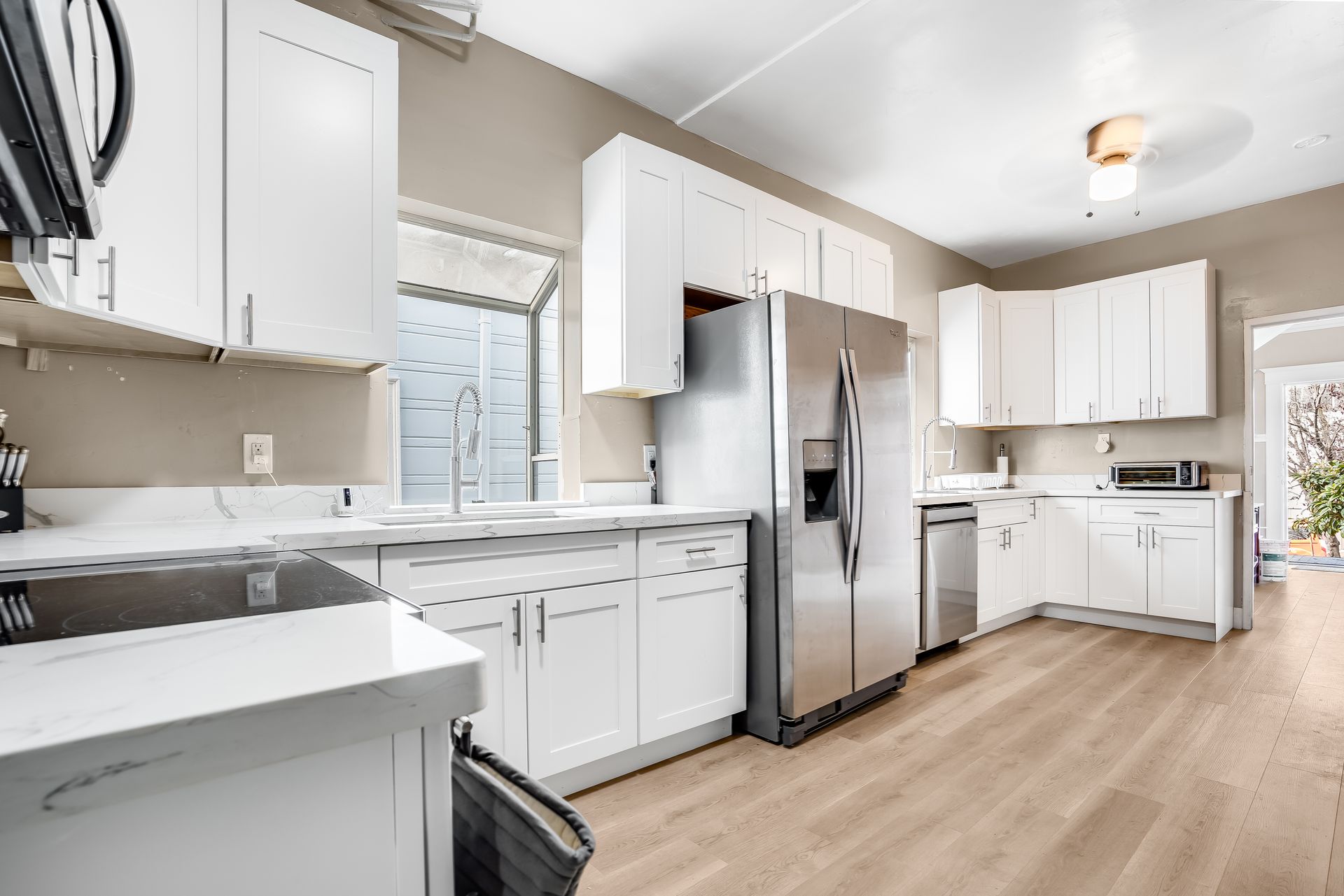 Bright, white kitchen with stainless steel appliances, wood-look floors, and neutral walls.