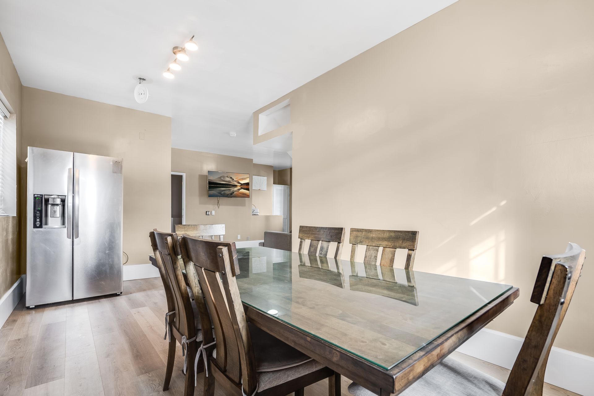 Dining room with wooden table, chairs, and a stainless steel refrigerator.