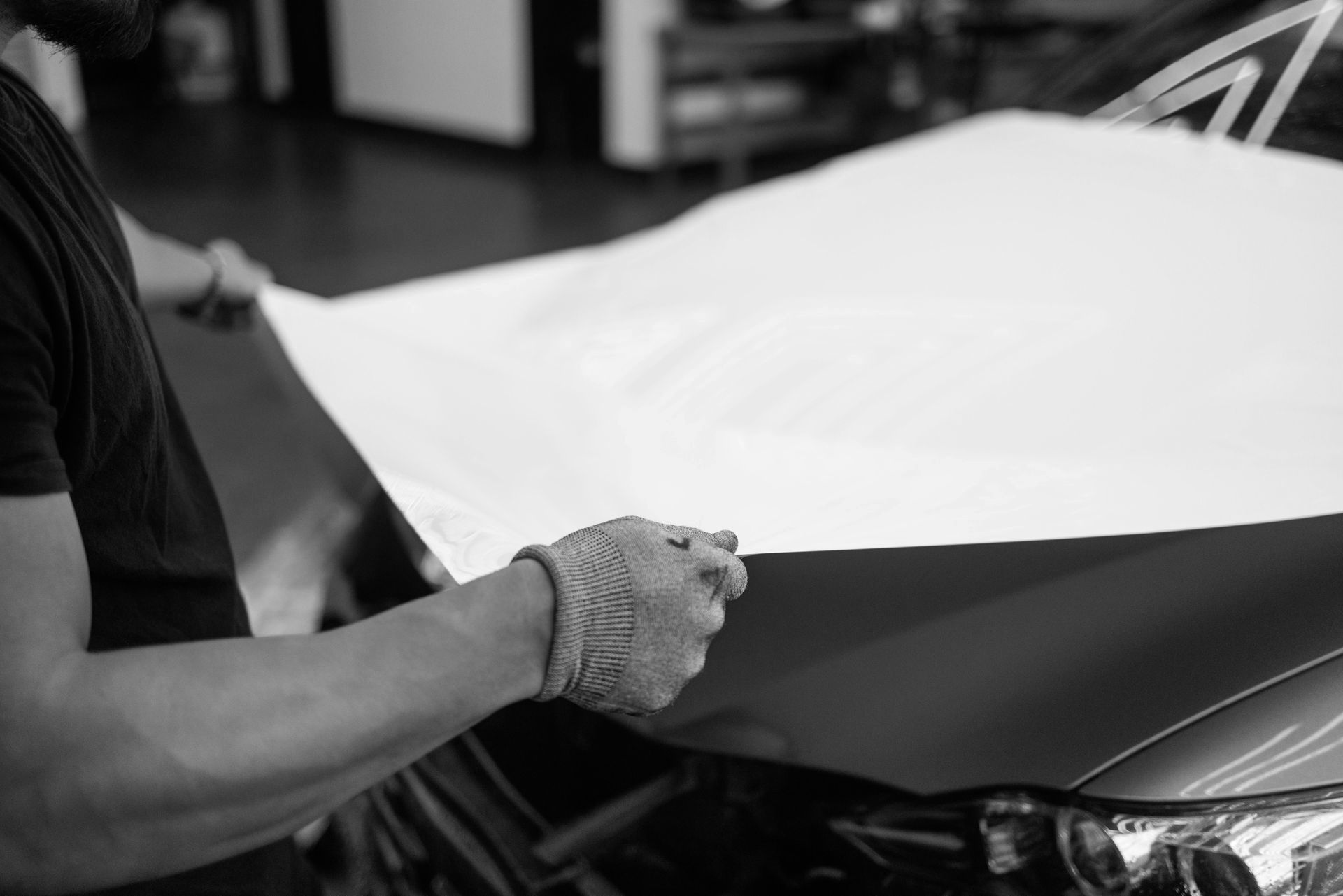 A man is holding a piece of paper over the hood of a car.