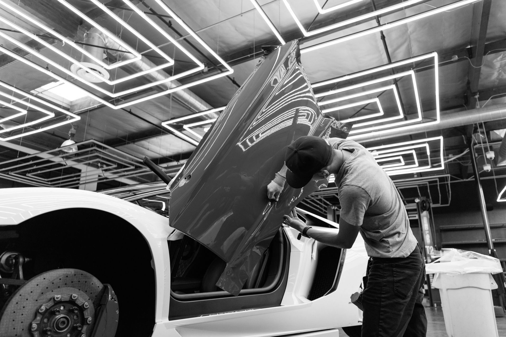 A man is working on a car in a garage with the hood up.