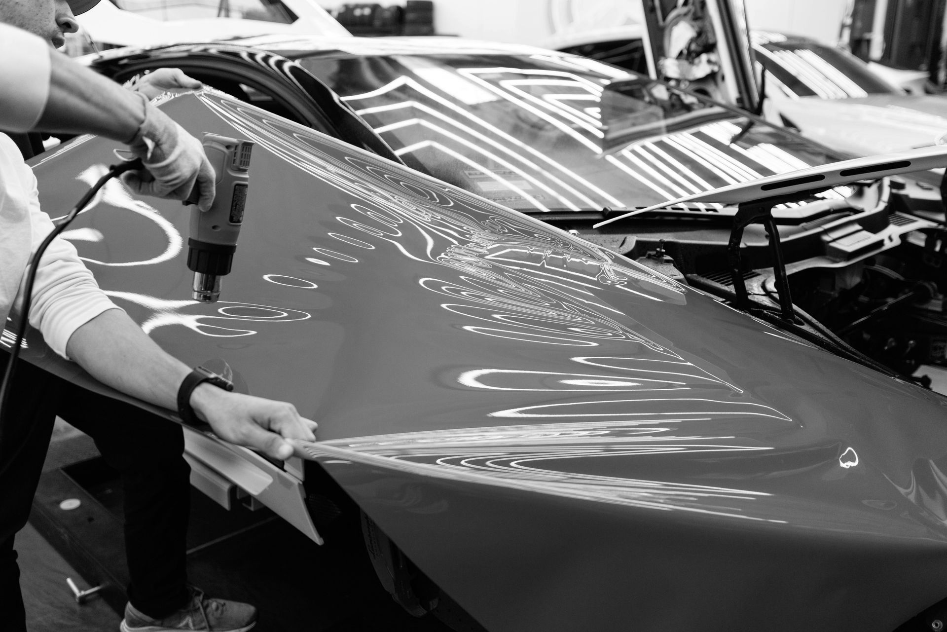 A man is wrapping a car with a drill in a black and white photo.