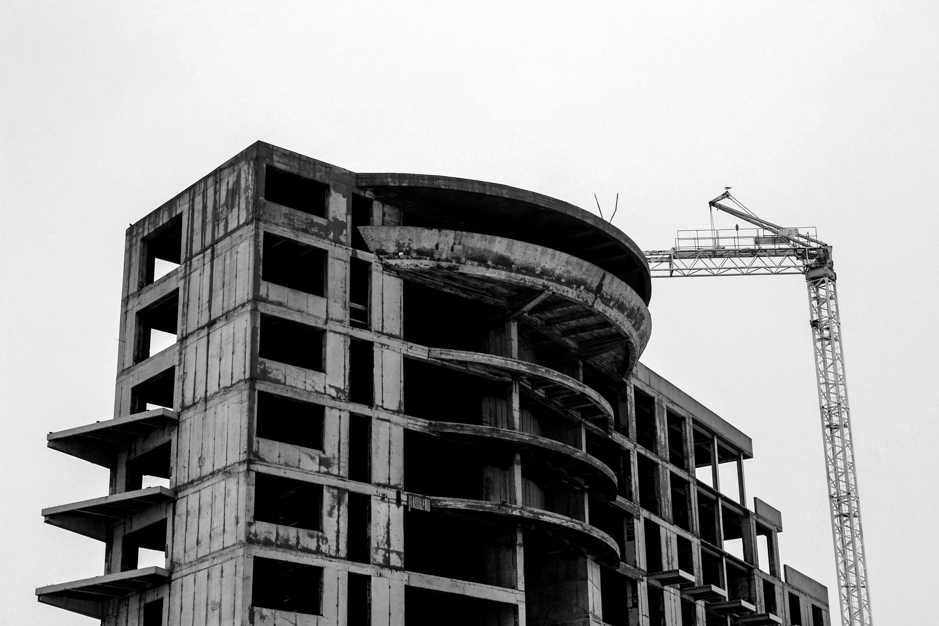 A black and white photo of a building under construction with a crane in the background.