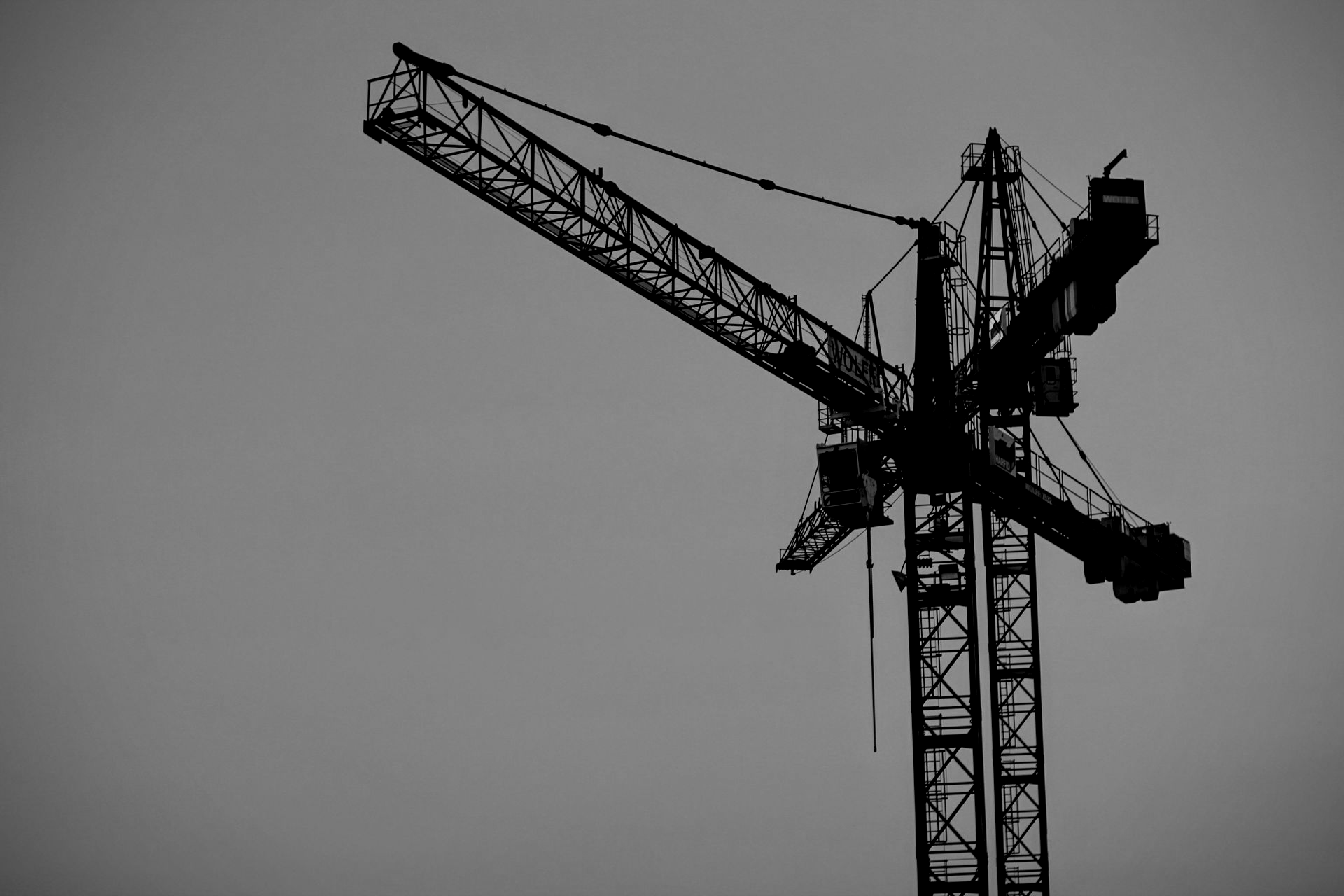 Red construction crane against a pale blue and pink sky.
