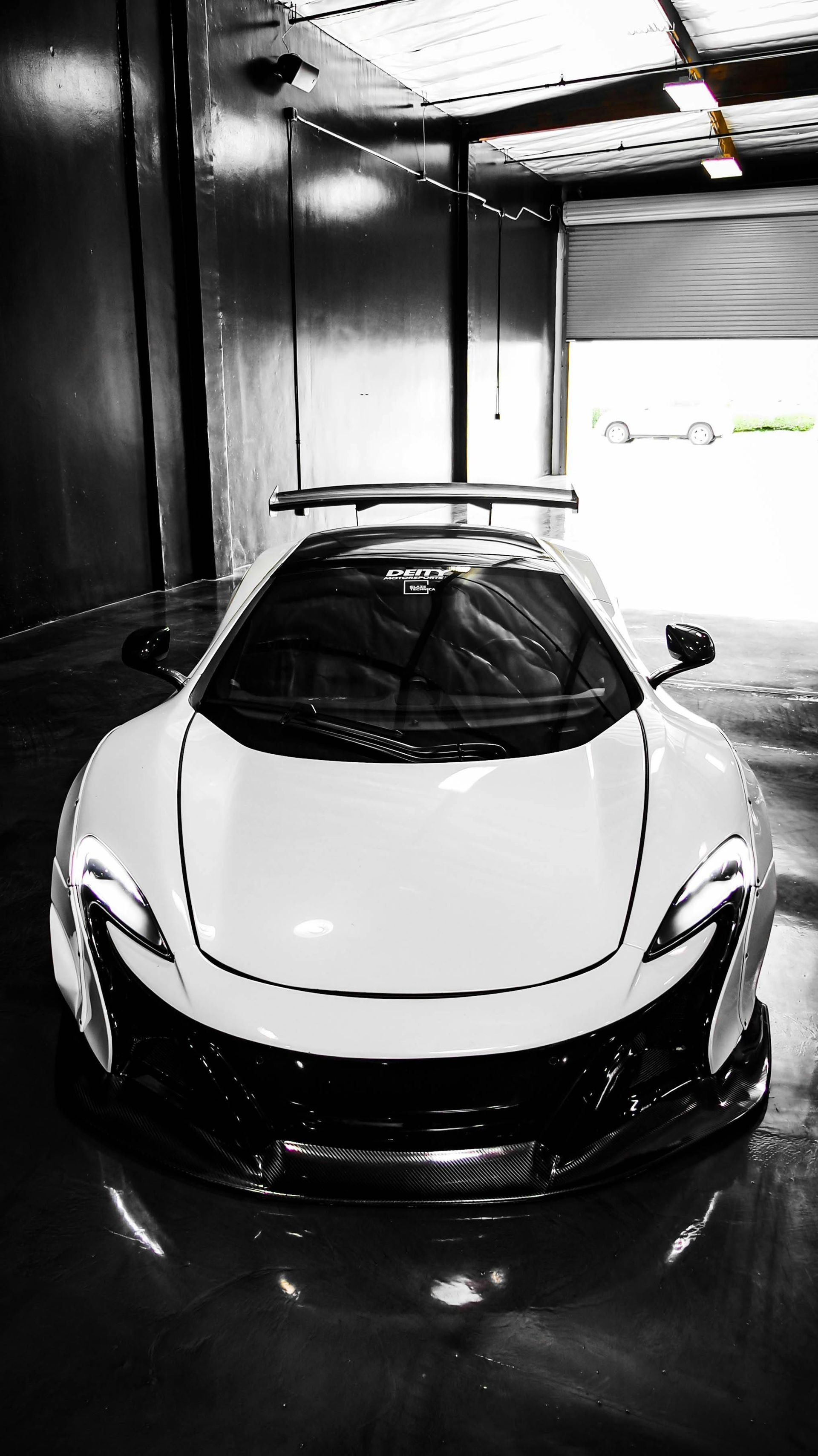 A black and white photo of a white sports car in a garage.