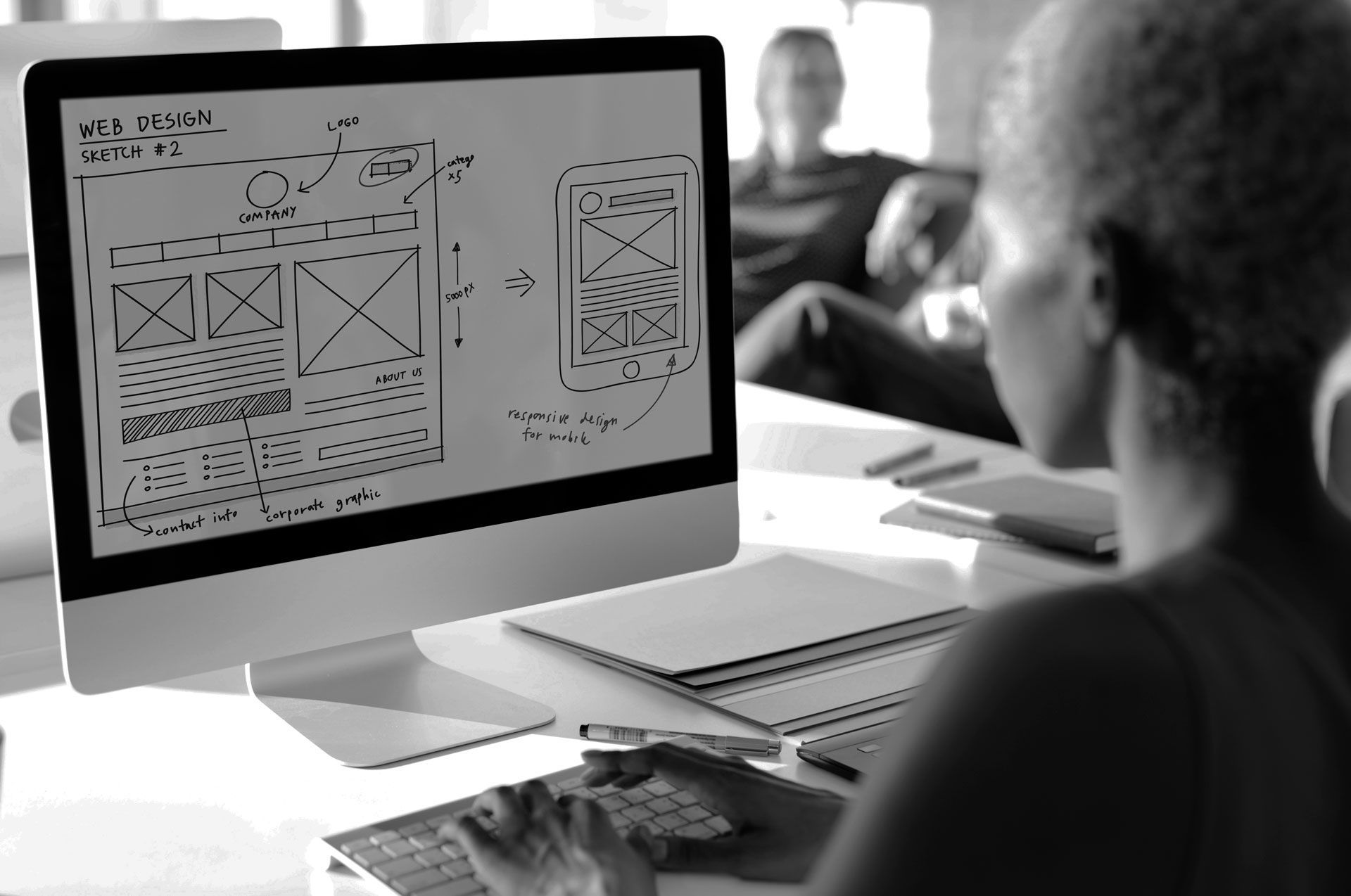 A person is holding a cell phone in front of a laptop computer.