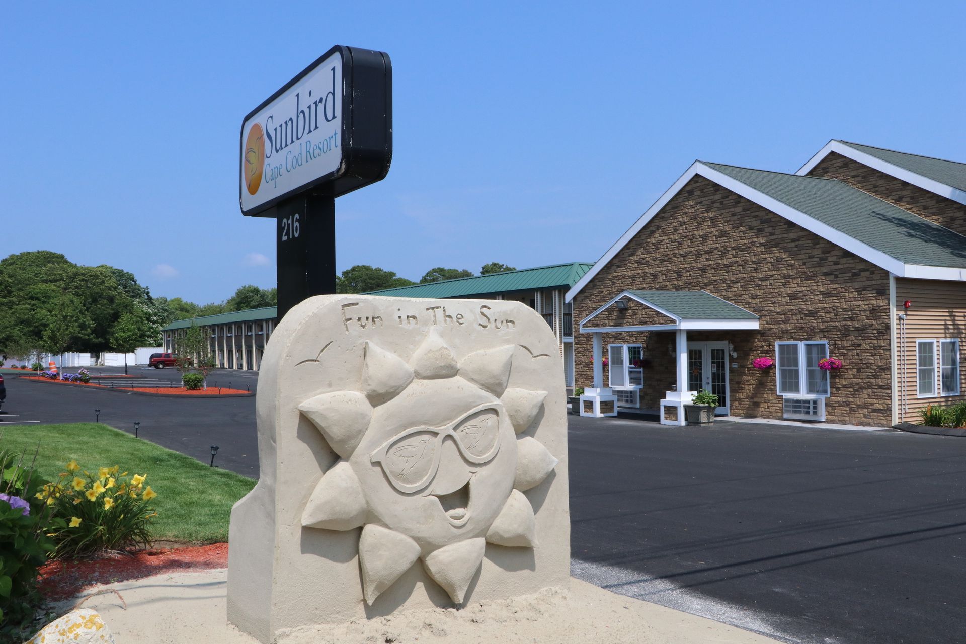 Sandford Motel sign and carved smiling sun sculpture; beige building, black asphalt.