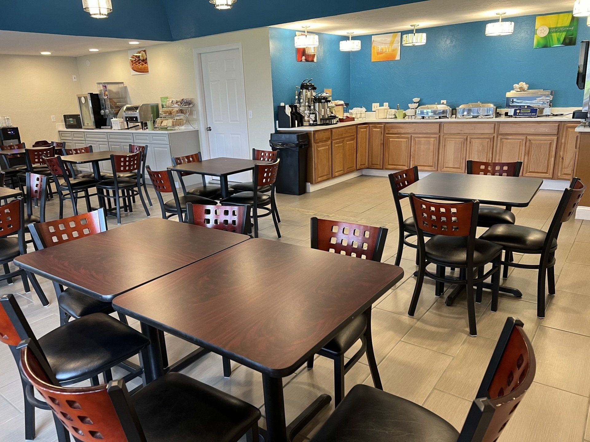 Restaurant breakfast area with tables, chairs, and a buffet station with food and coffee.