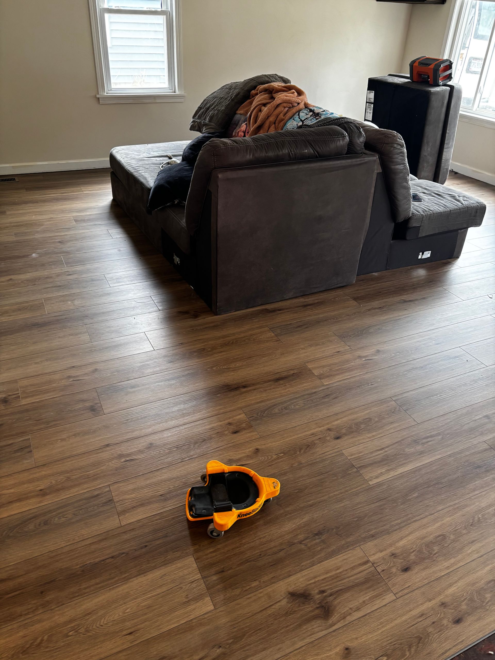 Brown and black sectional sofa in a room with wood-look flooring. A yellow and black toy is on the floor.