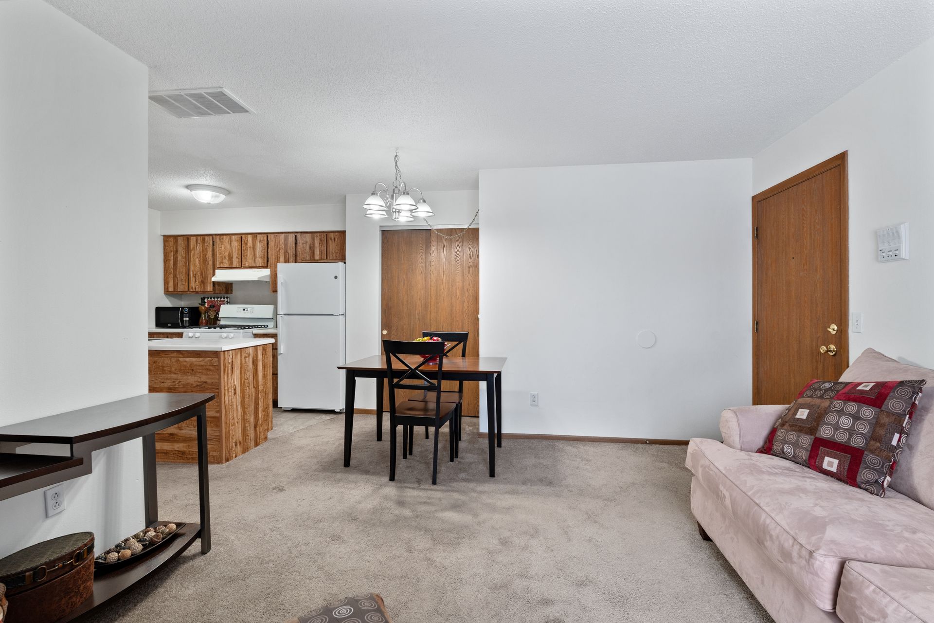 Photo of a living room with a dining room in the background, as well as the kitchen