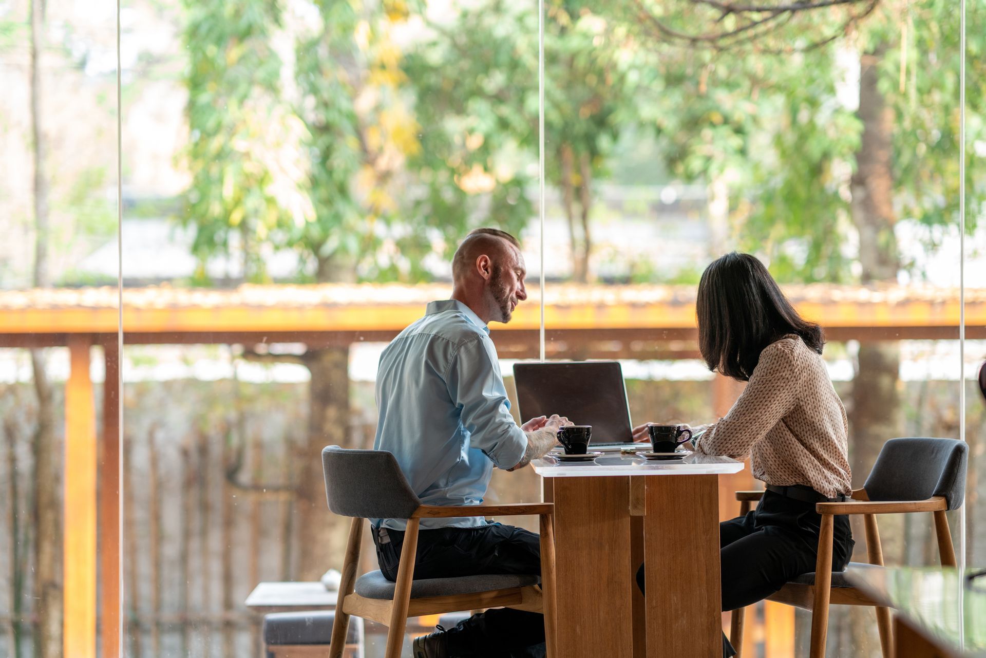 A man and a woman are sitting at a table with laptops.