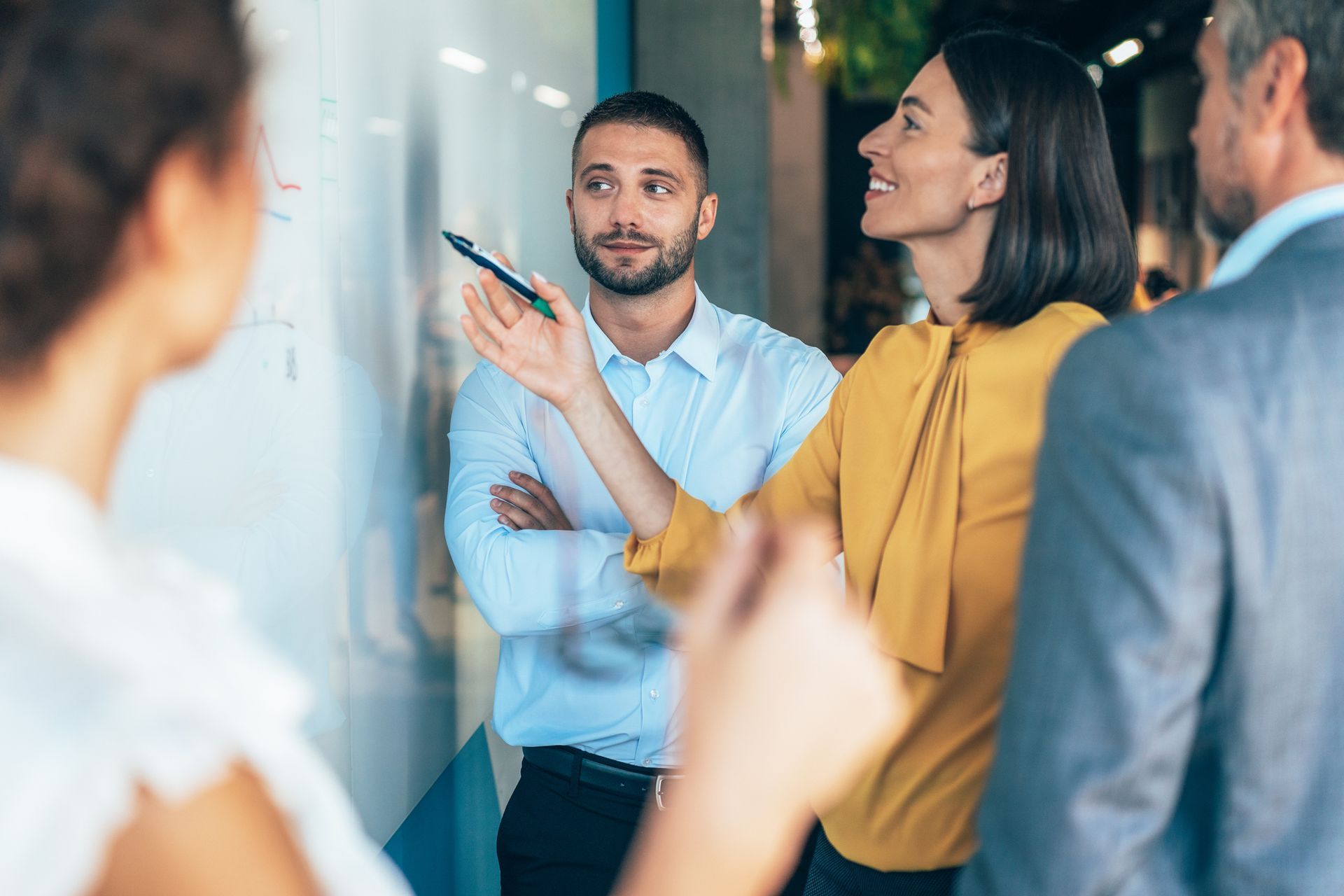 A group of people are standing around a whiteboard.