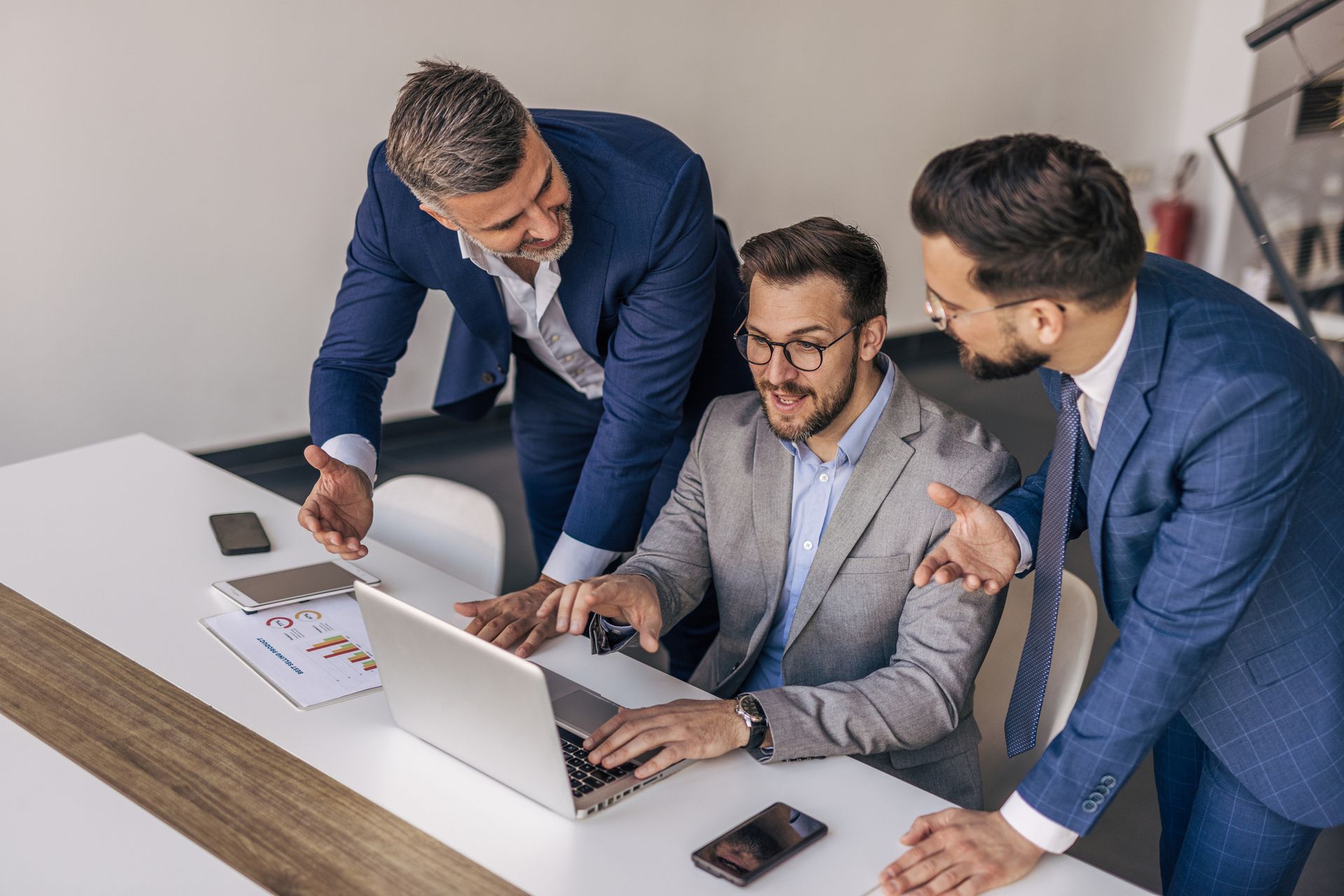 A group of businessmen are looking at a laptop computer.