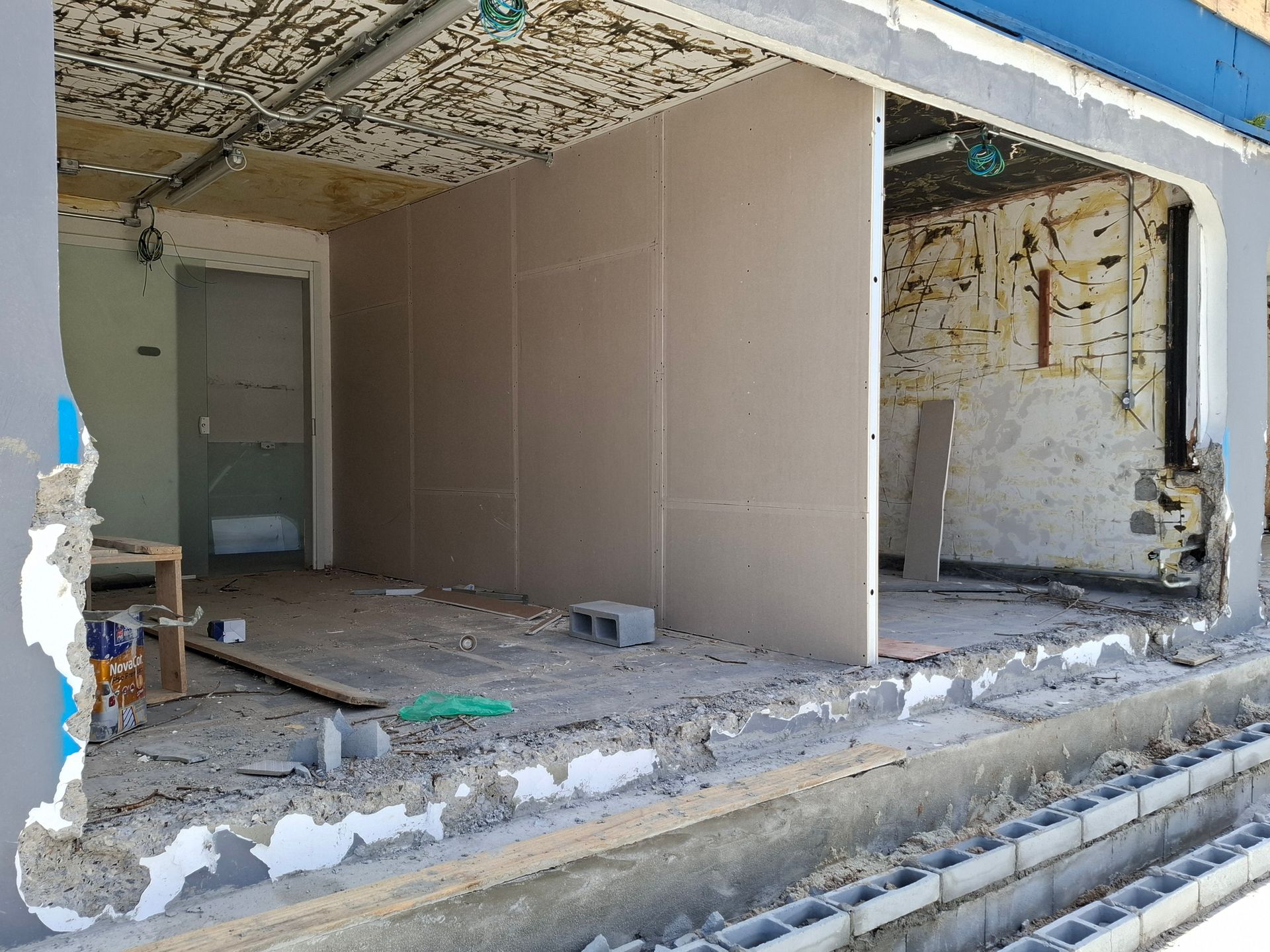 Interior view of a building under construction, showing drywall, concrete blocks, and exposed infrastructure.