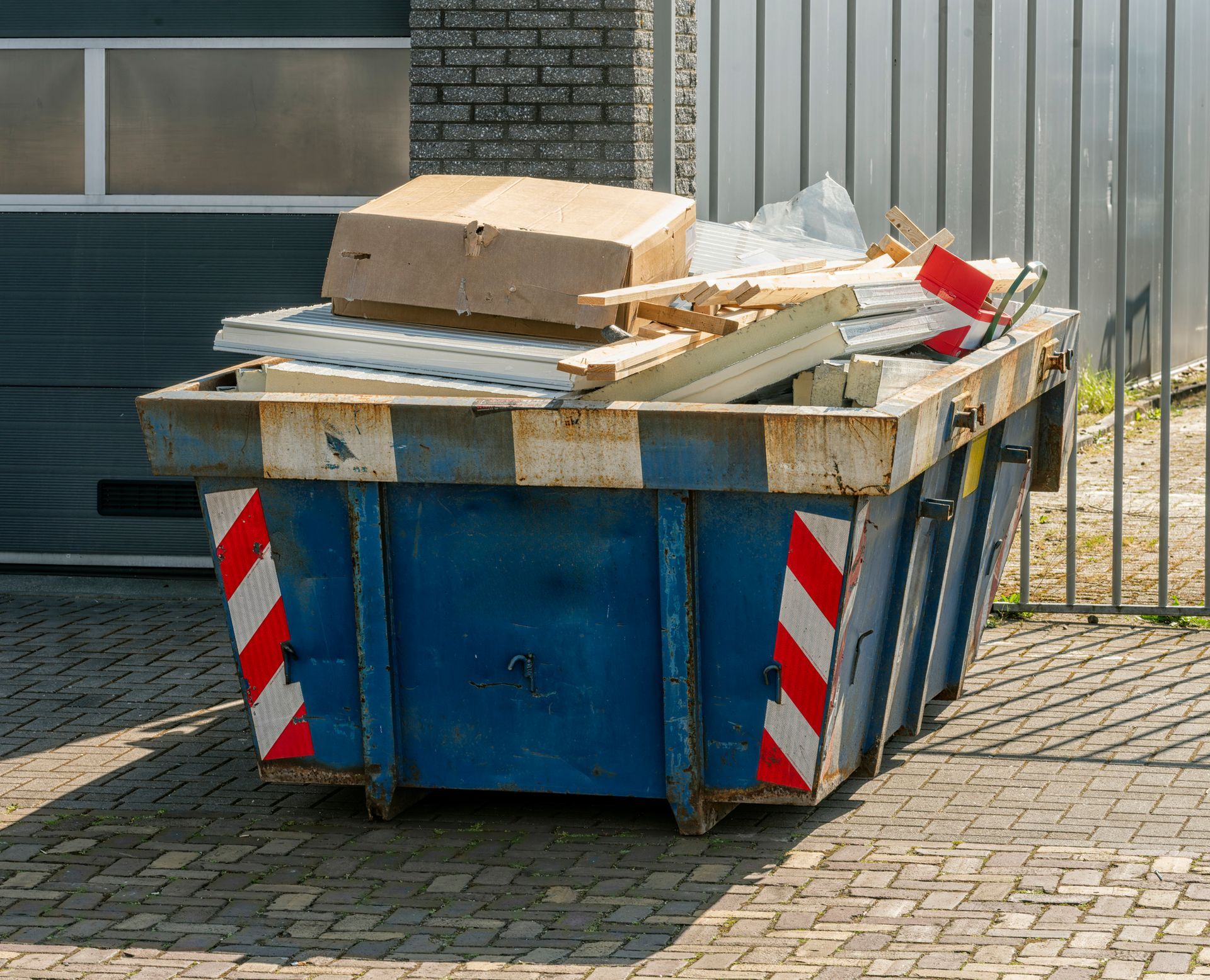 Blue and white dumpster filled with construction debris, outdoors.