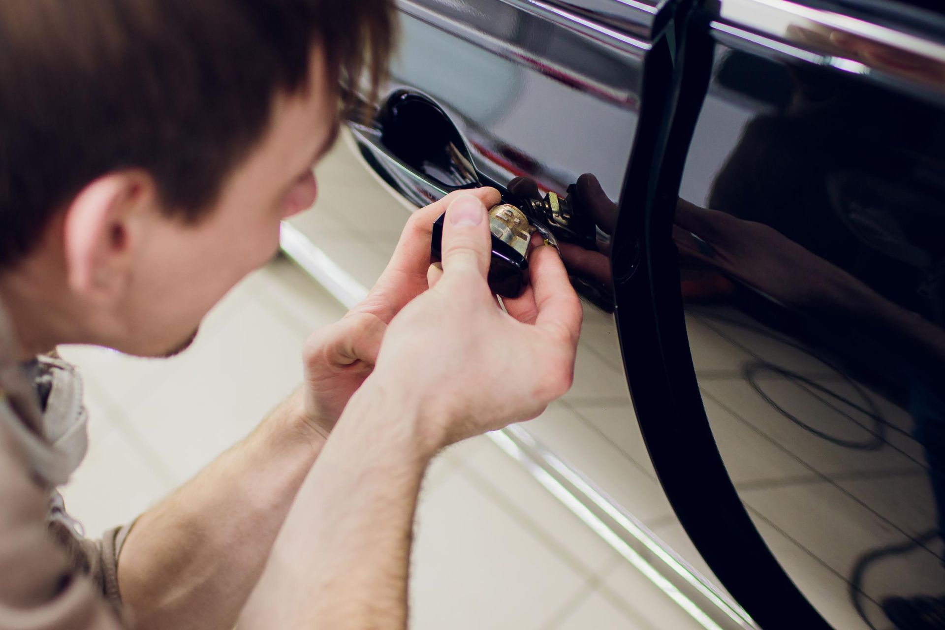 Person using a key to unlock a black car door close-up