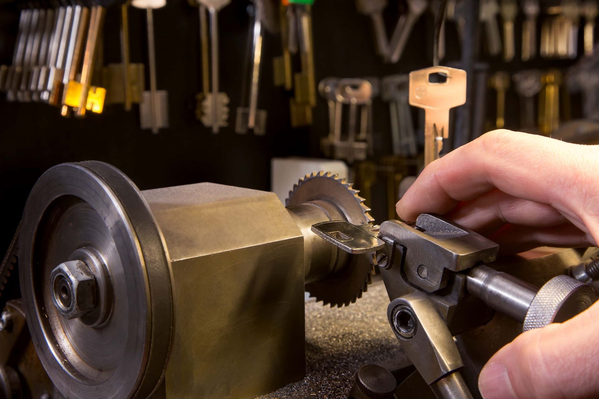 Hands operating a metal lathe, cutting a gear-like brass piece in a workshop