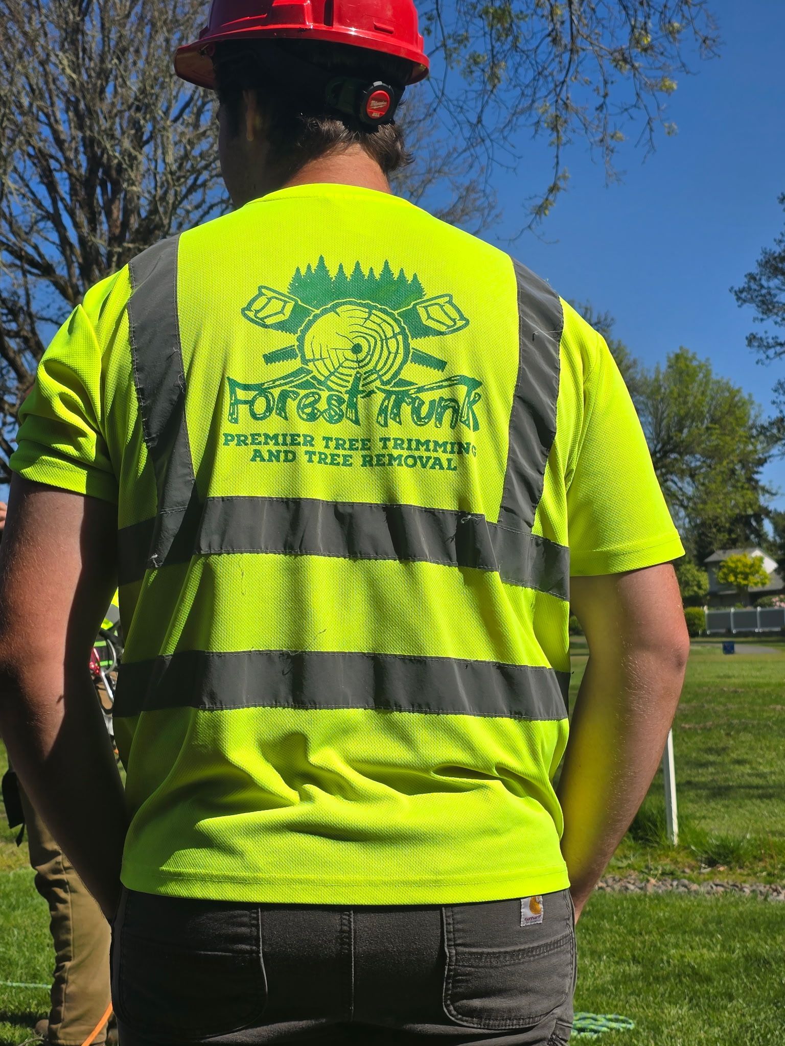 A man wearing a hard hat and a yellow vest with the word forest on it