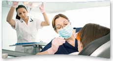 Dentist carrying out a dental examination while her assistant helps position the lighting