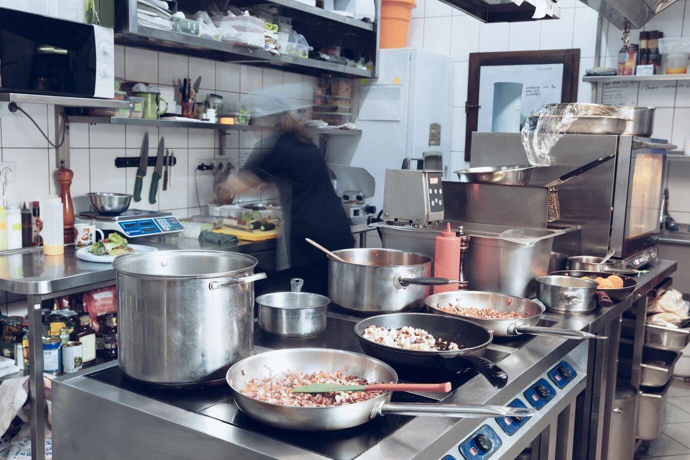 A kitchen with a lot of pots and pans on the stove.