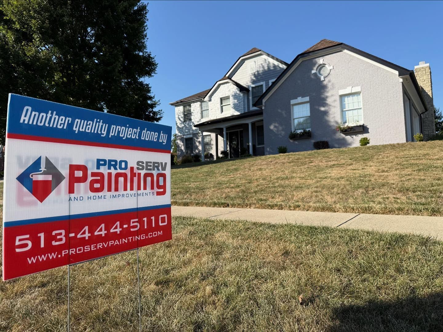 Yard sign advertising painting services in front of a suburban house on a sunny day