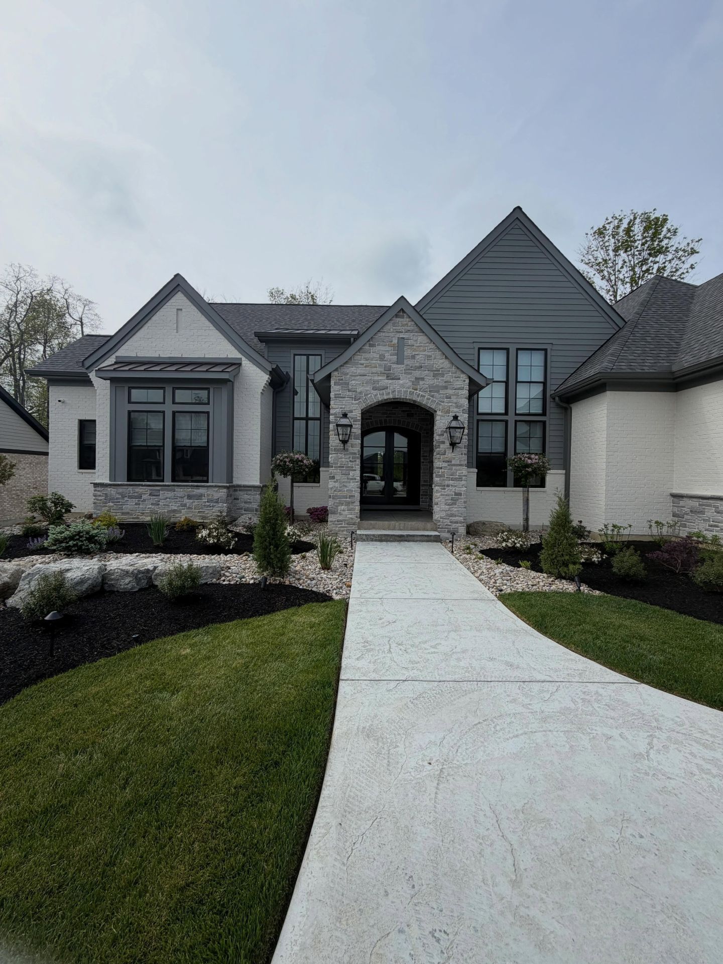Modern gray-and-white house with a curved white walkway and landscaped front yard