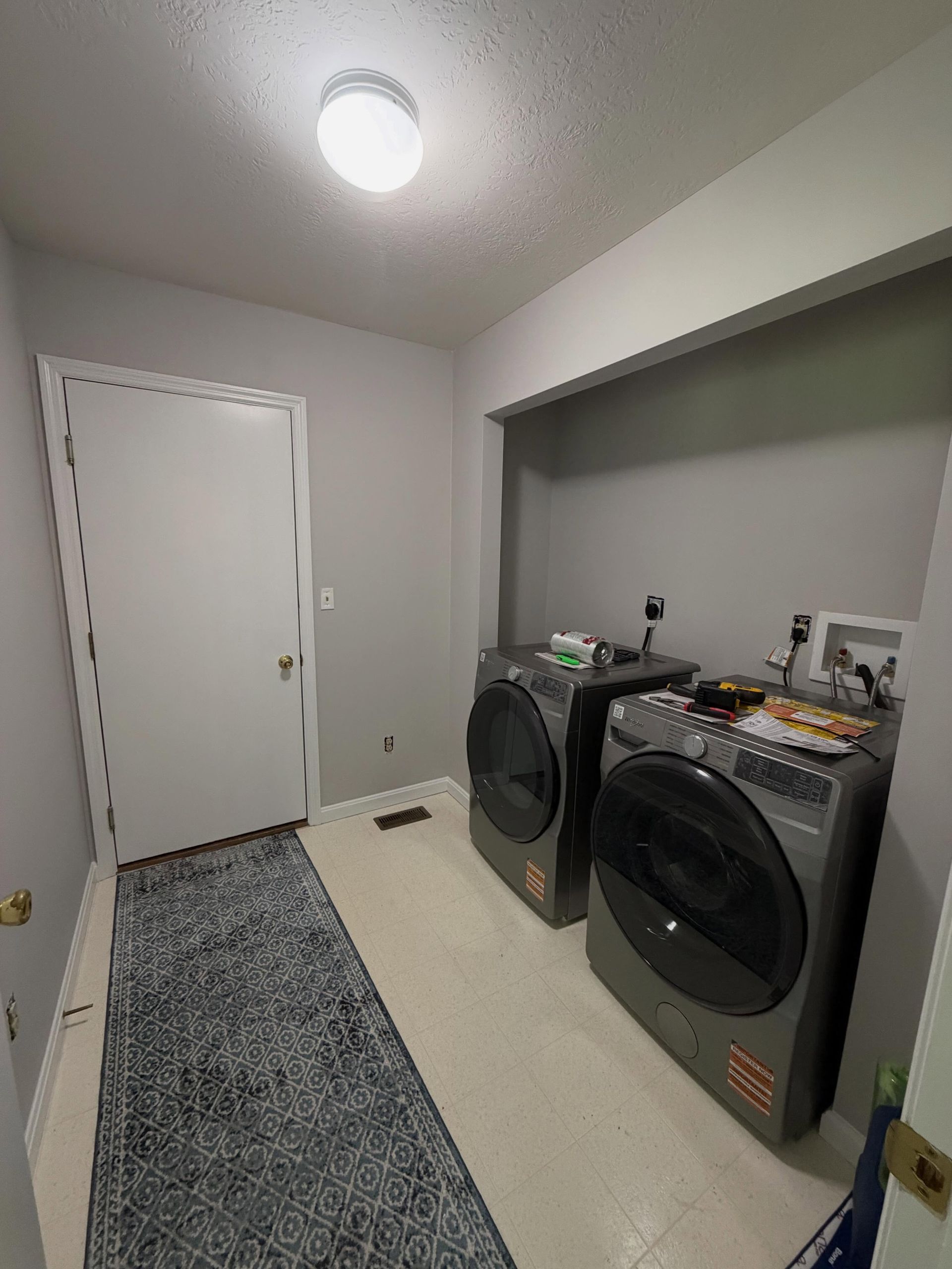 Laundry room with front-load washer and dryer, white door, and gray walls