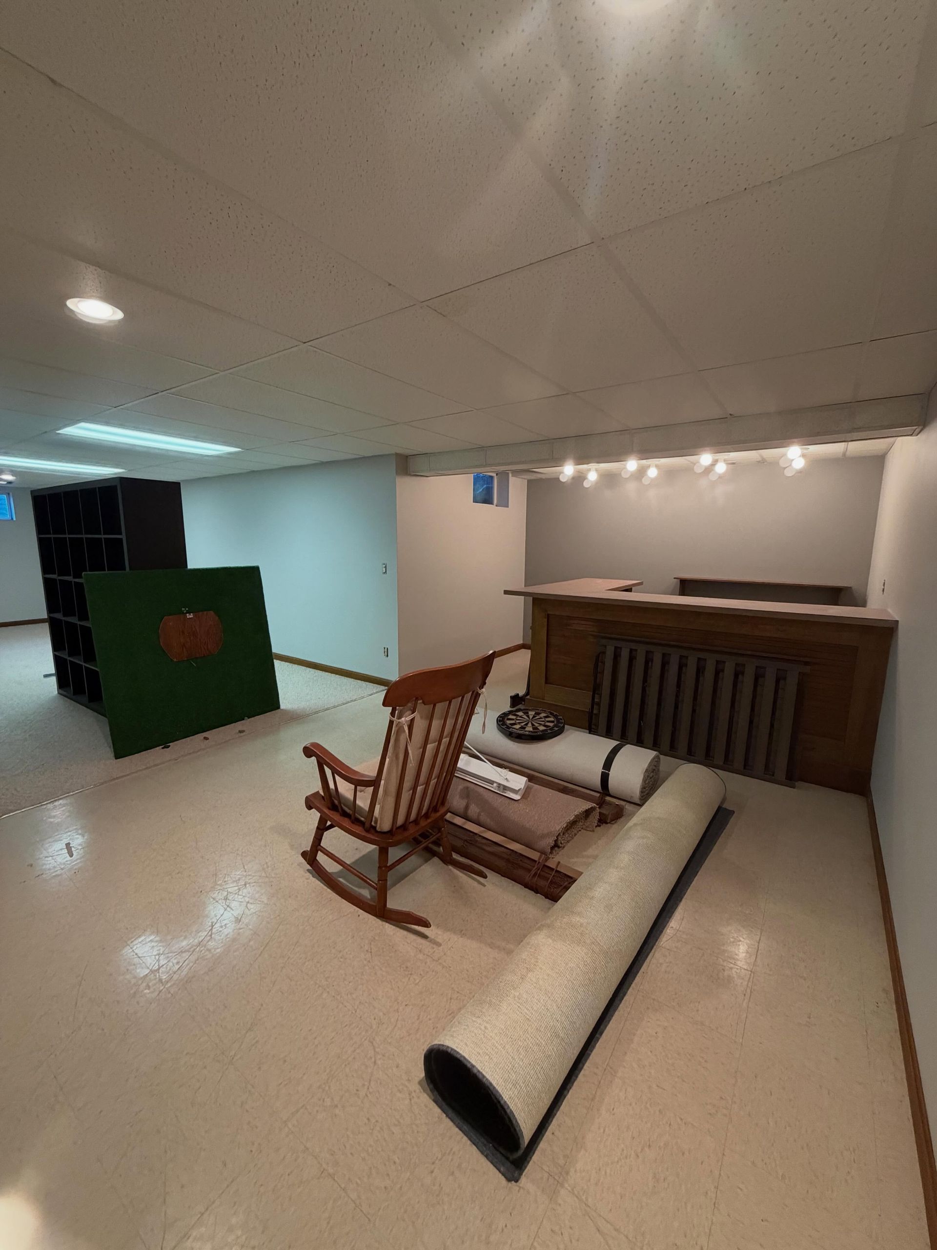 Indoor room with overturned chair, rolled carpet, and counter under fluorescent lights