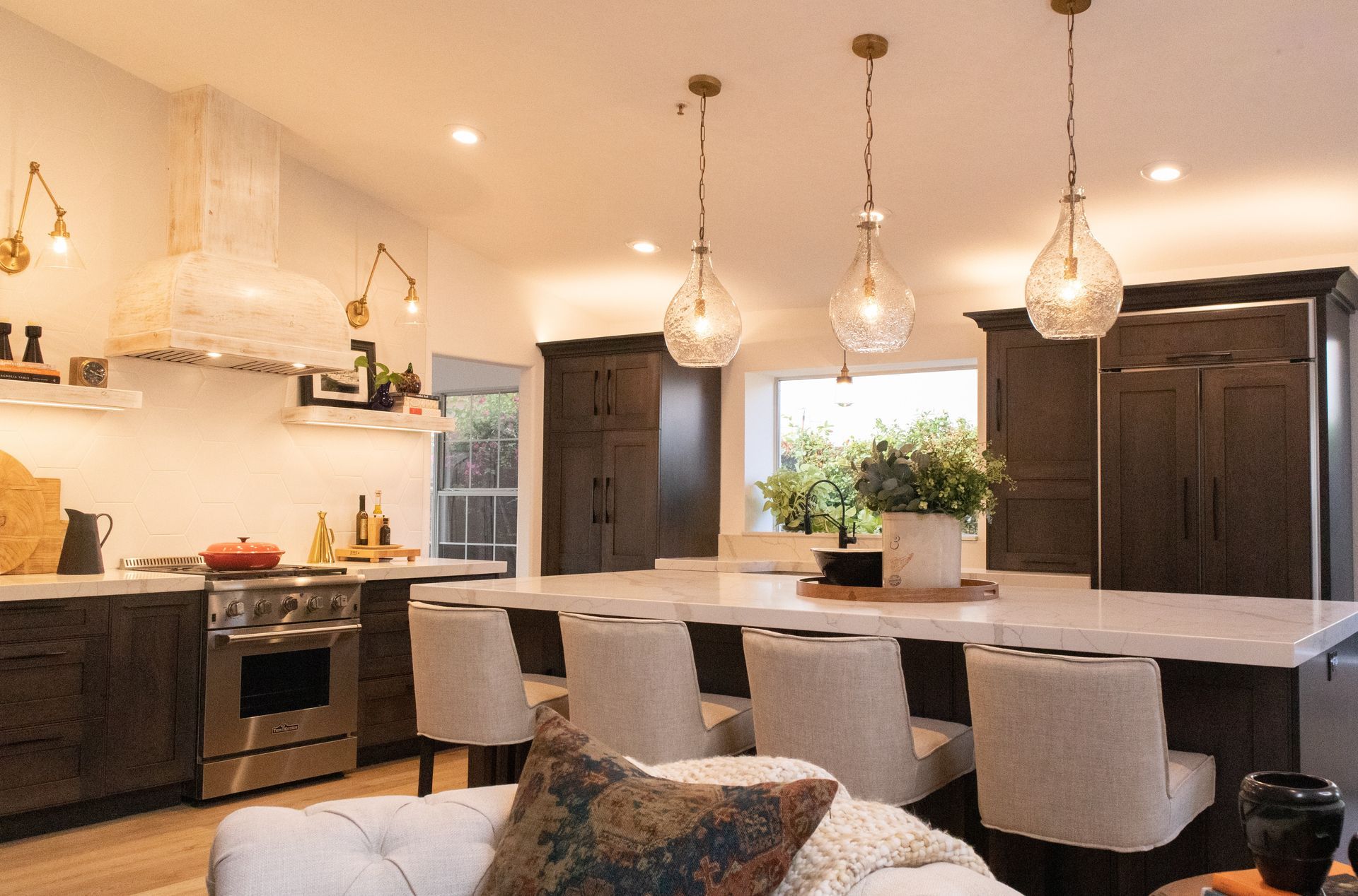 Modern kitchen with dark cabinetry, white countertops, and pendant lights.