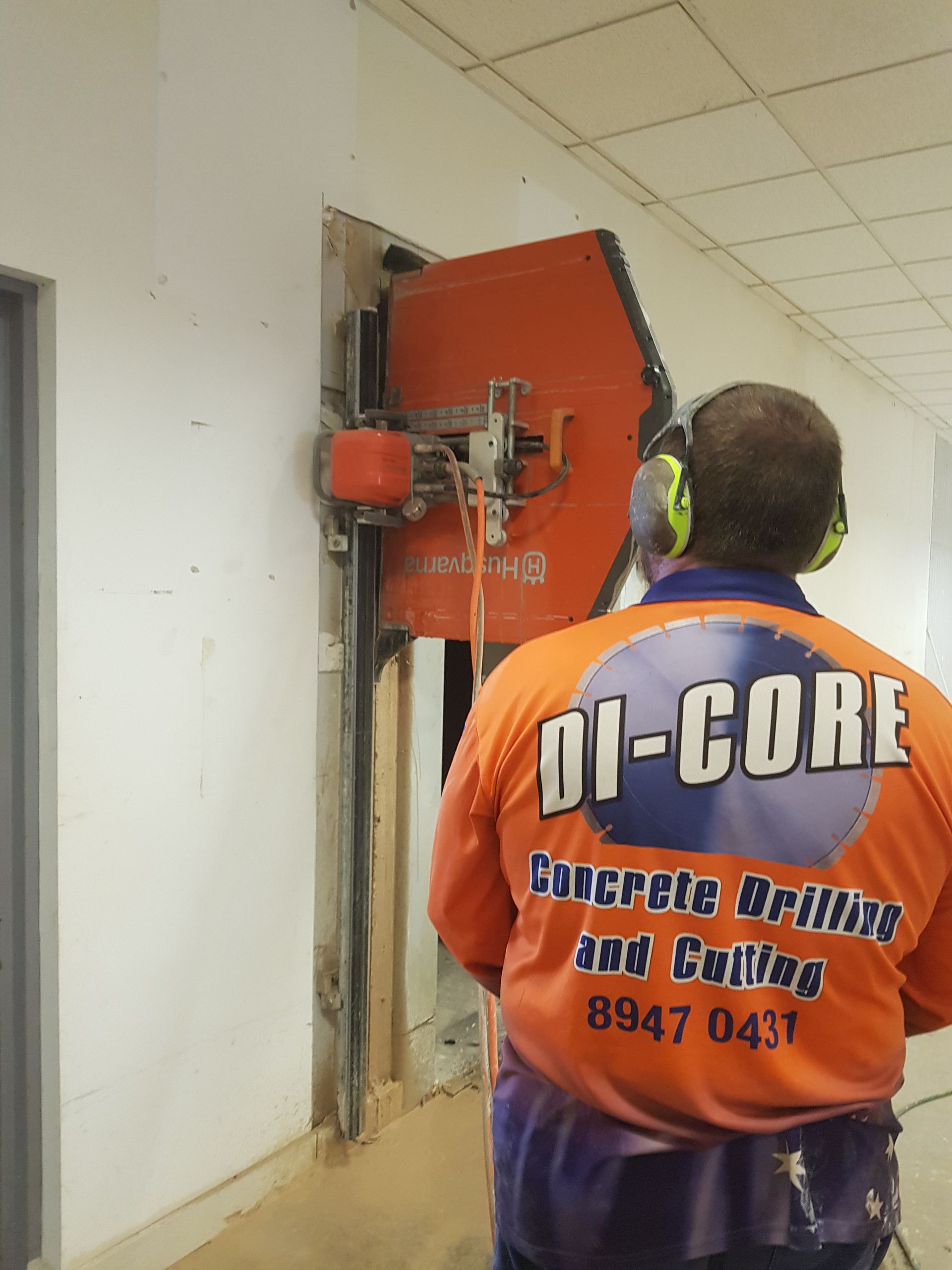 A Man is Standing in a Room With a Machine on the Wall — Di-Core Drilling and Cutting in Darwin, NT
