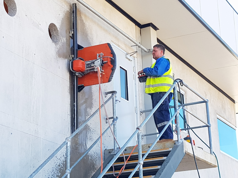 A Man is Cutting a Hole in a Blue Wall With a Circular Saw — Di-Core Drilling and Cutting in Darwin, NT