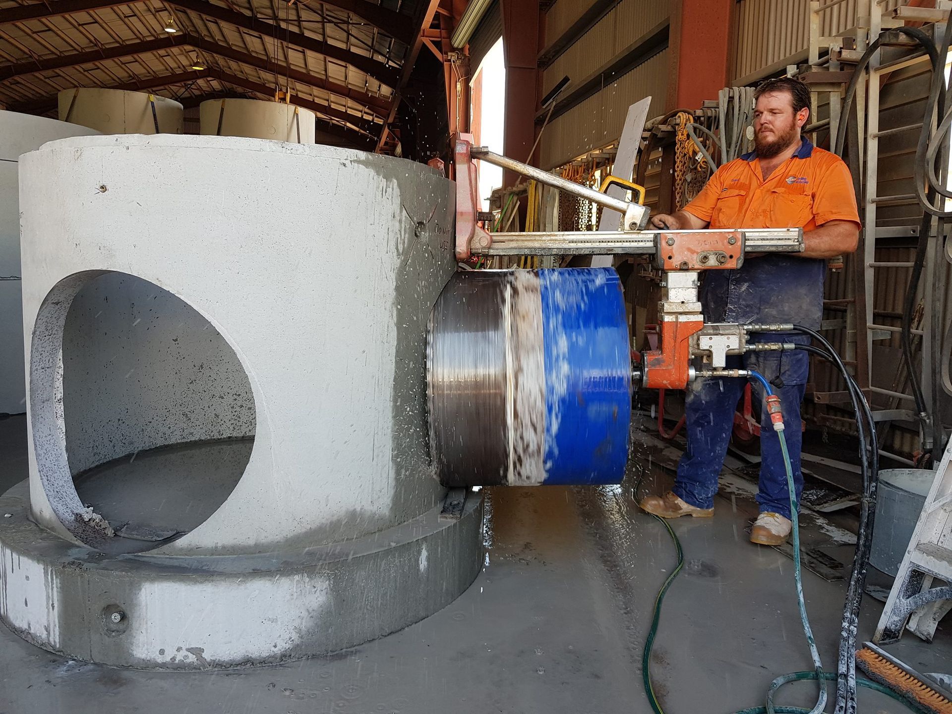 A man is using a machine to cut a hole in a concrete pipe — Di-Core Drilling and Cutting in Darwin, NT
