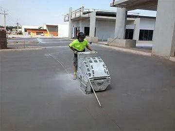 A Man is Using a Machine to Cut Concrete in a Parking Lot — Di-Core Drilling and Cutting in Darwin, NT