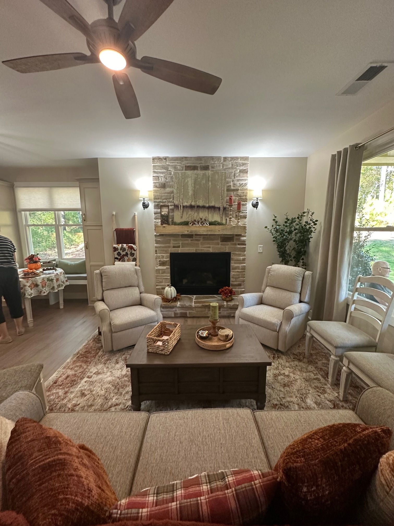 A living room filled with furniture and a fireplace with a ceiling fan.