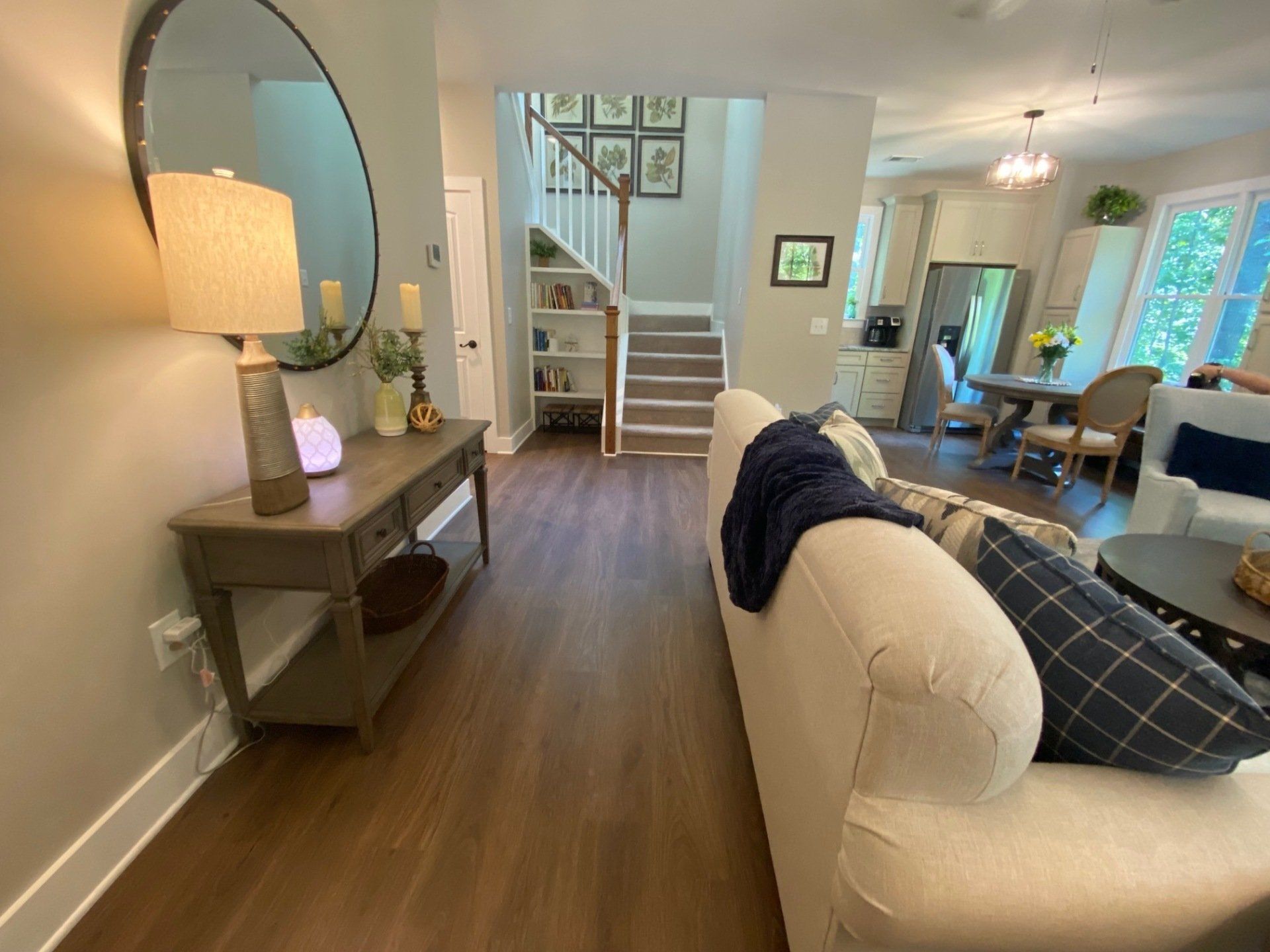 A living room with a couch , table , mirror and stairs.