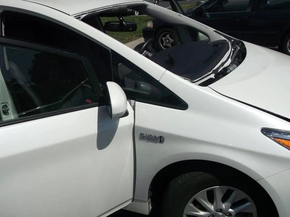 White Toyota Prius, driver's door open. Side mirror visible. 