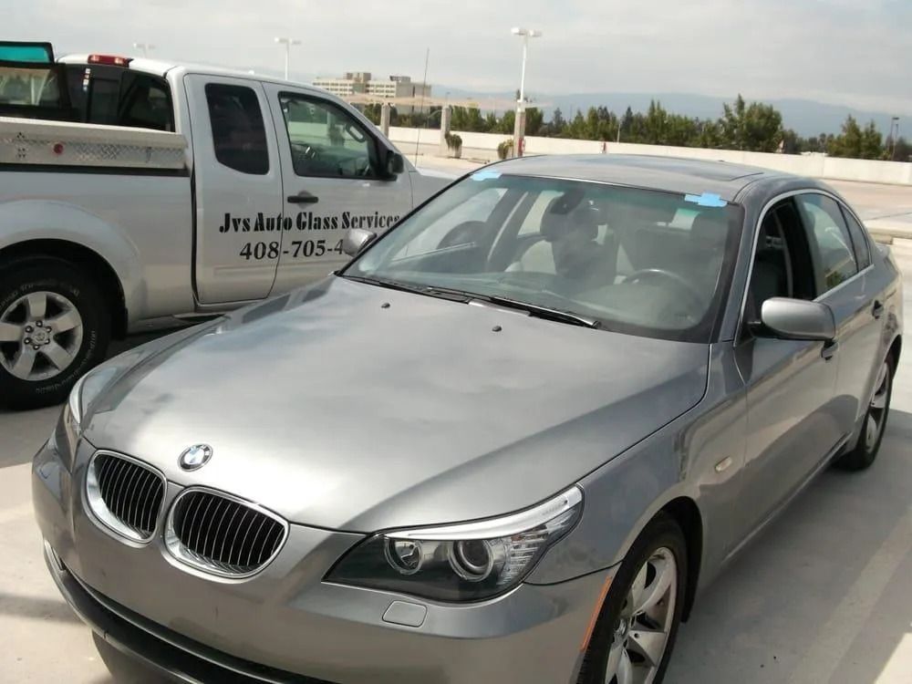 Gray BMW sedan parked next to a white pickup truck with 