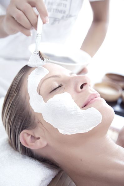 Einer Frau wird eine weiße Maske aufs Gesicht gelegt.