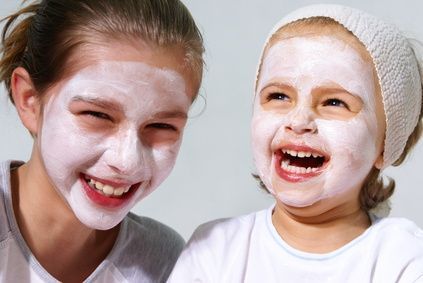 Zwei junge Mädchen tragen weiße Gesichtsmasken und lächeln.