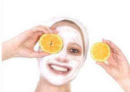 Eine Frau mit einer weißen Maske im Gesicht hält Orangenscheiben vor ihre Augen.