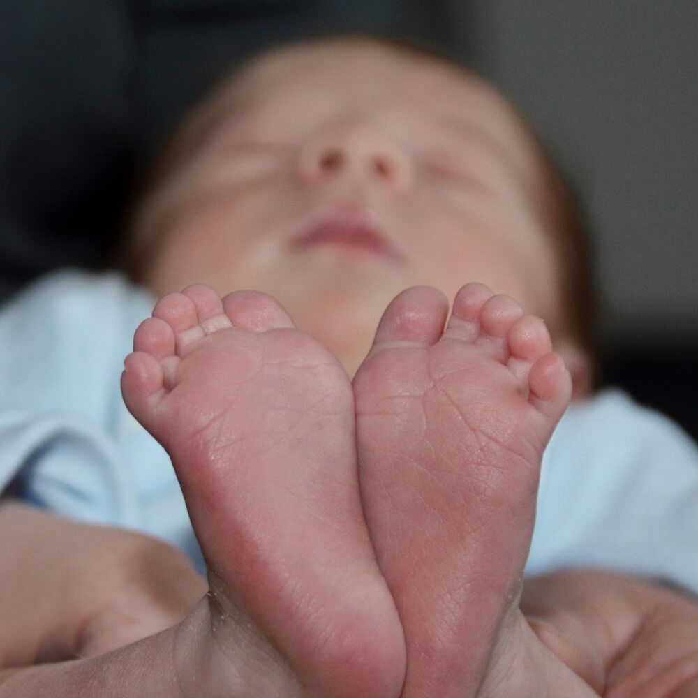 De voeten van een baby worden vastgehouden door een persoon
