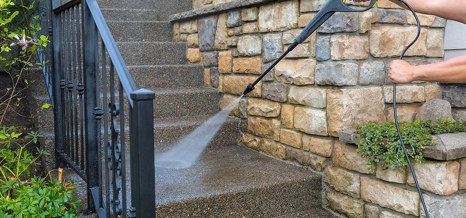 A Person is Using a High Pressure Washer to Clean a Stone Wall and Stairs — South Coast Pressure Washer in Albion Park, NSW